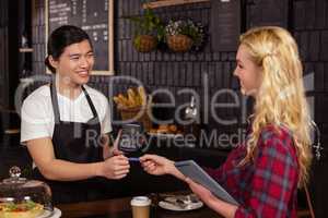 Smiling barista taking credit card from customer