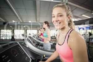 Fit woman running on the treadmill while listening music