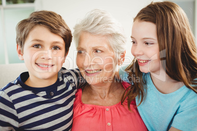 Grandmother and grandchildren sitting together on sofa