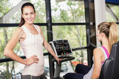 Trainer woman helping woman doing exercise bike