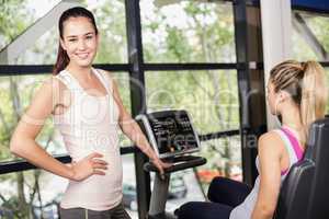 Trainer woman helping woman doing exercise bike