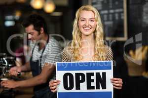 Portrait of waitress showing open sign