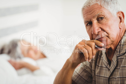 Portrait of worried senior man sitting on bed