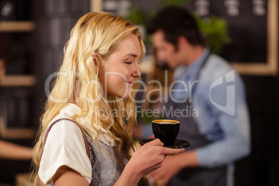 Portrait of smiling pretty customer smelling cup of coffee