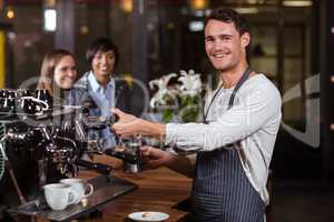 Smiling barista making hot milk with coffee machine