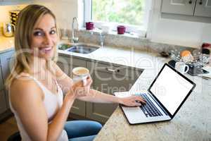 Pretty blonde woman having coffee and using laptop