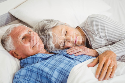 Senior man lying awake next to asleep senior woman