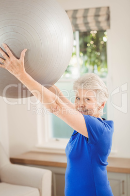 Senior woman lifting exercise ball while exercising Senior woman lifting exercise ball while exercising