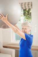 Senior woman lifting exercise ball while exercising