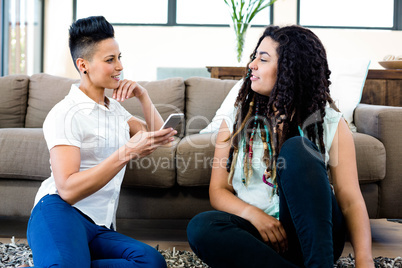 Lesbian couple sitting on rug and talking to each other