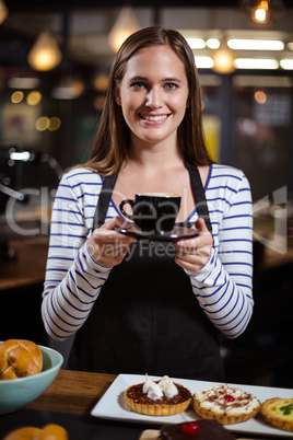 Smiling barista holding coffee