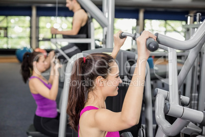 Fit woman using weight machine
