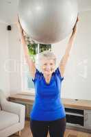 Senior woman lifting exercise ball while exercising