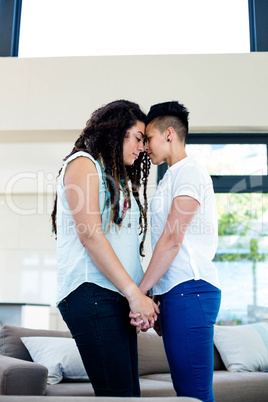 Romantic lesbian couple standing face to face and holding hands