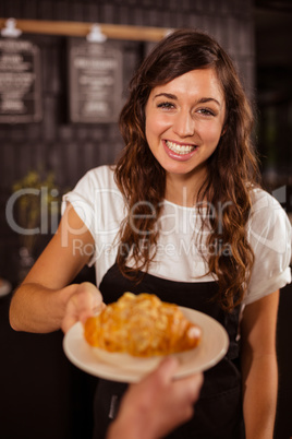 Pretty waitress giving croissant to customer