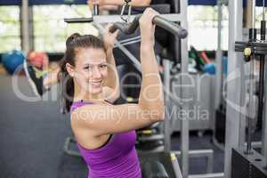 Fit woman using weight machine