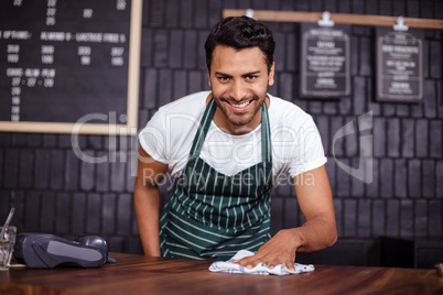 Smiling barista cleaning counter