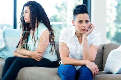 Unhappy lesbian couple sitting on sofa