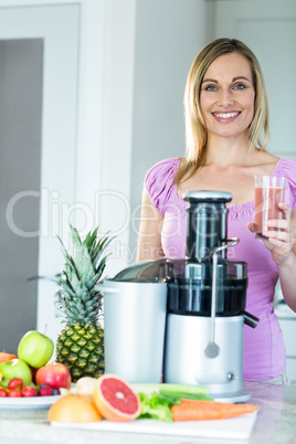 Blonde woman holding a smoothie glass in the kitchen