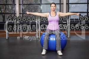 Determined woman lifting dumbbells on fitness ball