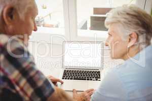 Senior couple talking while using laptop