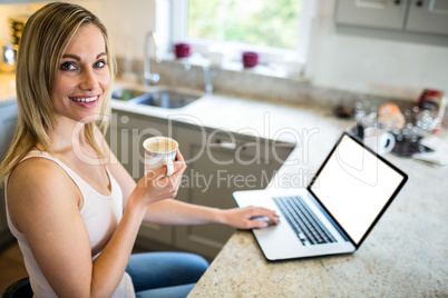 Pretty blonde woman having coffee and using laptop