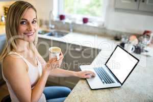 Pretty blonde woman having coffee and using laptop