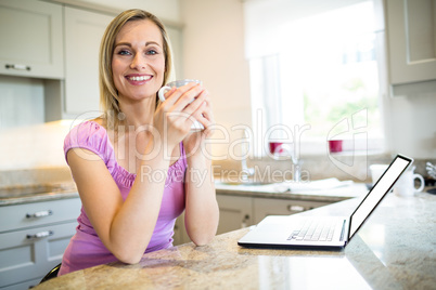 Pretty blonde woman having coffee and using laptop