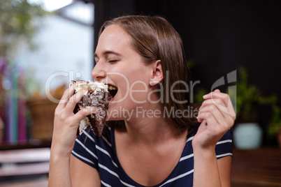 Pretty woman eating piece of cake with hand