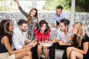 Woman blowing birthday candles with friends