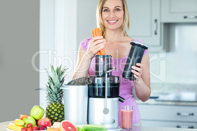 Blonde woman preparing a smoothie in the kitchen