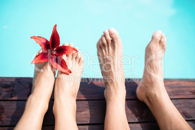 Couple bare feet against swimming pool