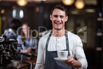 Smiling barista holding cappuccino
