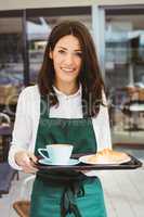 Waitress holding tray with coffee and croissant