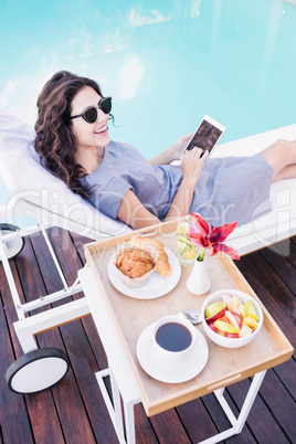 Young woman relaxing on a sun lounger near poolside