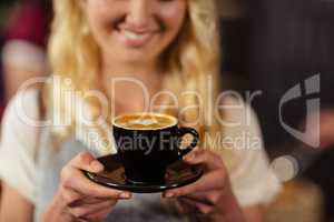 Portrait of smiling pretty customer holding cup of coffee