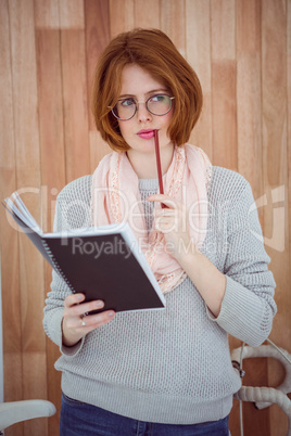 pensive hipster woman with a notepad and pencil