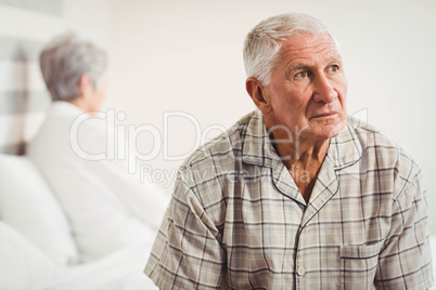 Upset senior man sitting on the opposite ends of the bed