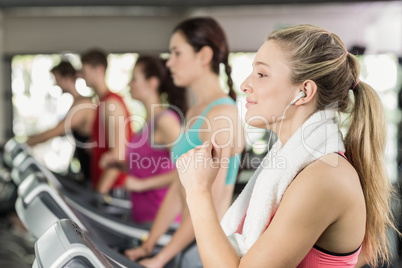 Fit woman running on the treadmill while listening music