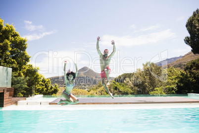 Couple jumping into swimming pool