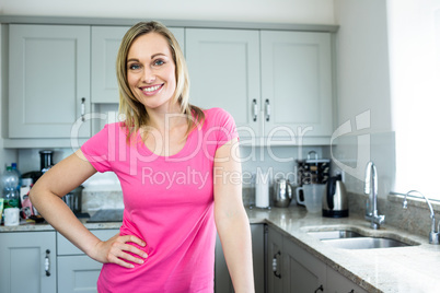Pretty blonde woman standing in the middle of her kitchen