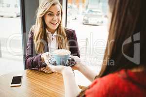 Cute blonde girl having a coffee served by her friend