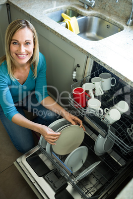 Pretty blonde woman emptying the dishwasher