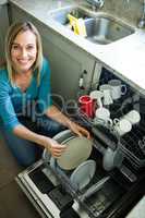 Pretty blonde woman emptying the dishwasher