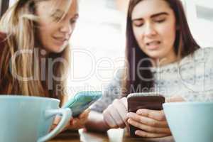 Friends using smartphone and having coffee