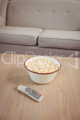 Bowl of popcorn and television remote on table