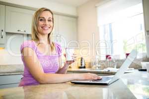 Pretty blonde woman having coffee and using laptop