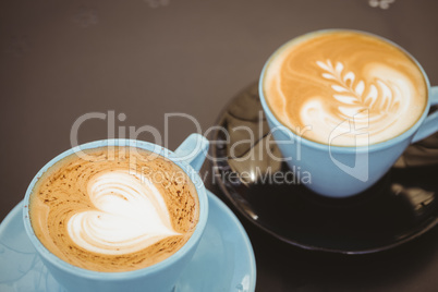 Cup of cappuccino with coffee art on wooden table