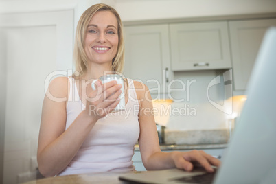 Pretty blonde woman having coffee and using laptop