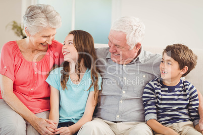 Grandparents and grandchildren sitting together on sofa